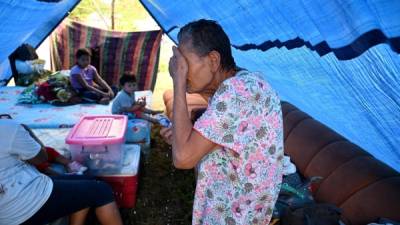 An evacuated elderly woman gestures next to children resting in a tent in El Progreso municipality, Yoro department, Honduras, on November 6, 2020, after the passage of hurricane Eta. - Scores of people, including 50 in Guatemala, have died as the remnants of Hurricane Eta on Thursday unleashed floods and triggered landslides on its deadly march across Central America. (Photo by Orlando SIERRA / AFP)