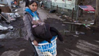 A resident of Staten Island's New Dorp Beach neighborhood carries a basket full of clothes and other items on her street that was devastated by Superstorm Sandy, Monday, Nov. 5, 2012, in New York. Although many areas of the metropolitan area are beginning to return to normal, neighborhoods of Staten Island's southern shore remain without power as the cleanup continues. (AP Photo/ John Minchillo)