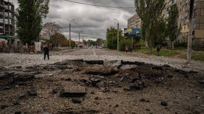 Un policía camina junto a un cráter luego de un ataque con misiles en Dnipro el 10 de octubre de 2022, en medio de la invasión rusa de Ucrania. El jefe del ejército ucraniano dijo que las fuerzas rusas lanzaron al menos 75 misiles contra Ucrania el lunes por la mañana.