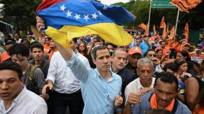 El líder opositor venezolano Juan Guaidó ondea una bandera nacional durante una manifestación para exigir una fecha para las elecciones presidenciales en Caracas.