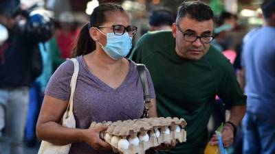 A woman wears a protective face mask to prevent the spread of the new Coronavirus, at the Agriculture Market, in Tegucigalpa, on March 14, 2020. - Honduran government has prohibited citizens from Europe, China, Iran, and South Korea the entrance to the country. (Photo by ORLANDO SIERRA / AFP)