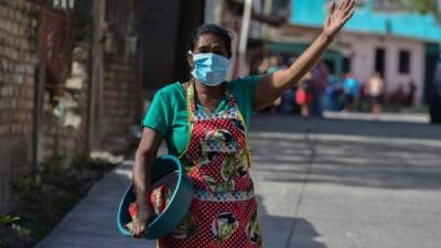 Una mujer que vende tortillas camina por una calle de la colonia Abraham Lincoln de Tegucigalpa que fue cerrada hoy por militares y personal de Salud para evitar más contagios. (Photo by Orlando SIERRA / AFP)