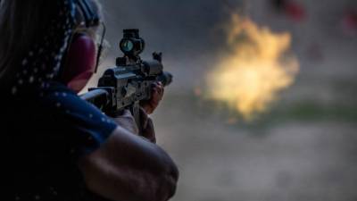 Foto referencial de una mujer que dispara un arma automática.