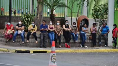 Ciudadanos hacen fila para ingresar a una agencia bancaria en la capital de Honduras. AFP
