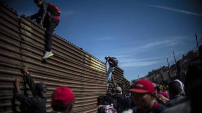 Un grupo de migrantes centroamericanos, en su mayoría hondureños, trepan por la frontera entre México y Estados Unidos, cerca del cruce de El Chaparral, en Tijuana, estado de Baja California, México.
