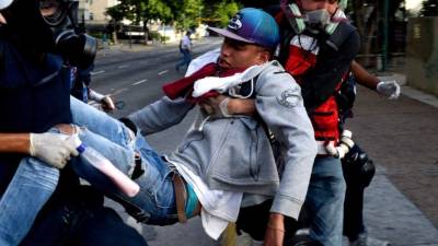 TOPSHOT - An opposition demonstrator wounded during clashes with riot police is carried away by medics during a protest against Venezuelan President Nicolas Maduro, in Caracas on June 26, 2017. A political and economic crisis in the oil-producing country has spawned often violent demonstrations by protesters demanding Maduro's resignation and new elections. The unrest has left 75 people dead since April 1. / AFP PHOTO / FEDERICO PARRA