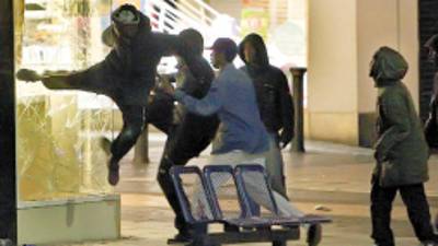 People try to kick in the window of a jeweller's shop near the Bullring shopping centre in Birmingham, central England, as violence spread outside London Monday, Aug. 8, 2011. Violence and looting spread across some of London's most impoverished neighborhoods on Monday, with youths setting fire to shops and vehicles, during a third day of rioting in the city that will host next summer's Olympic Games. (AP Photo / David Jones, PA) UNITED KINGDOM OUT, NO SALES, NO ARCHIVE