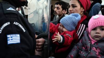Una mujer carga a su hija mientras un policía impide que cruce a Macedonia, que ayer cerró su frontera. Foto: AFP/Louisa Gouliamaki
