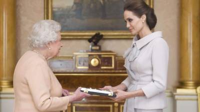 La reina Isabel II nombra 'dama de honor' a la actriz Angelina Jolie (d)por su campaña para tratar de poner fin a la violencia sexual en las zonas de guerra.