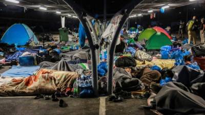 TOPSHOT - Migrants find shelter at a supermarket parking lot on September 17, 2020 in Lesbos before Police began an operation to rehouse thousands of homeless migrants at a new site after their camp was destroyed by fire last week. (Photo by - / AFP)