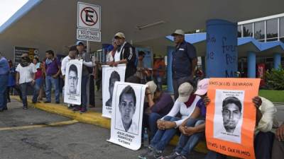 Los manifestantes sostienen fotos de algunos de los 43 estudiantes desaparecidos ya que bloquean las entradas del aeropuerto.
