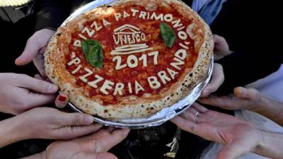 Tradicional. Varias personas sostienen una pizza en la plaza del Plebiscito en Nápoles, Italia. foto efe