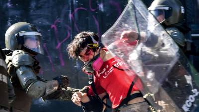 A demonstrator is detained by riot police during clashes outside La Moneda presidential palace, in Santiago, on October 28, 2019. - Chilean President Sebastian Pinera unveiled a major cabinet reshuffle on Monday as he battles to find a response to more than a week of street protests that have left at least 20 people dead. (Photo by Martin BERNETTI / AFP)