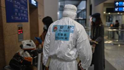 Un miembro del personal de seguridad del aeropuerto que usa equipo de protección, en medio de las preocupaciones por el brote de coronavirus COVID-19, acompaña a los pasajeros a un autobús que los llevará a su ciudad, después de llegar al Aeropuerto Internacional Pudong de Shanghai en Shanghai el 19 de marzo de 2020. China en marzo 19 no reportaron nuevos casos domésticos de coronavirus por primera vez desde que comenzó a registrarlos en enero, pero registraron un aumento en las infecciones del extranjero. / AFP / Hector RETAMAL