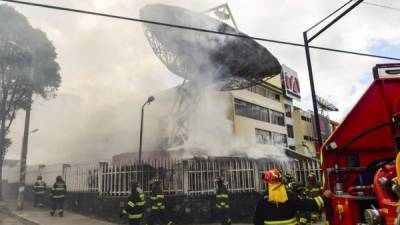 Los bomberos trabajan para extinguir un incendio en las oficinas de la estación de televisión ecuatoriana Teleamazonas después de que fue atacado por manifestantes durante el décimo día de una protesta por un aumento en el precio del combustible ordenado por el gobierno para asegurar un préstamo del FMI.