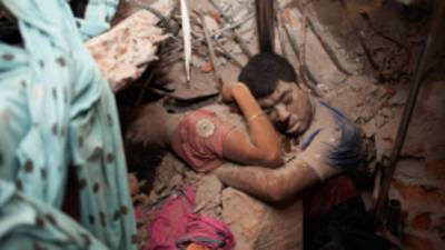 03_Garment Workers in Deathtrap_ Taslima Akhter_ Nobody knows who are they, what is the relation between them but the crude reality make them closer and may be they are trying to save each other and the last moment of their life from the death trap of Savar Rana Plaza_. Embrace in Death. Near about 438 workers died as building Collapse at Savar Rana Plaza. Most of them are women. Savar Dhaka, Bangladesh, 24th April 2013