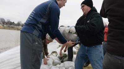 Voluntarios aplilan bolsas de arena en un intento por contener las crecidas agua de los ríos.