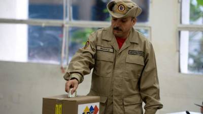 Un miembro de las milicias 'populares' civiles deposita su voto en la urna.