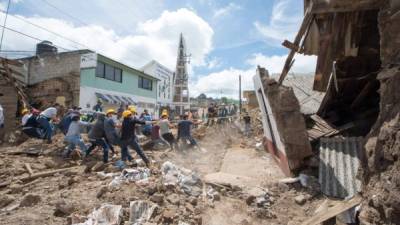 Soldados y voluntarios retiran una pared de una casa dañada en Joquicingo.