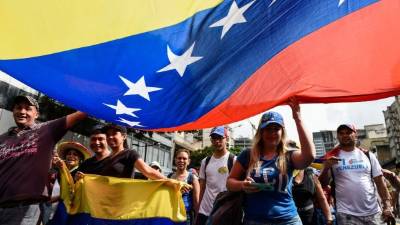 TOPSHOT - Venezuelan opposition leader and self-proclaimed acting president Juan Guaido flutters a Venezuelan national flag during a rally, as part of the 'Operation Freedom', in La Victoria, Aragua state, Venezuela on April 26, 2019. - Venezuelan opposition lawmaker Gilber Caro has been arrested by intelligence agents 'violating his parliamentary immunity,' the opposition-controlled legislature said on Friday. (Photo by Yuri CORTEZ / AFP)