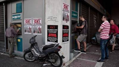 Atenienses retiran dinero de cajeros automáticos. las pancartas llaman a votar “no” en el referendum. Foto: AFP