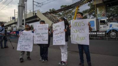 Un grupo de niños en el lugar de la tragedia sostiene pancartas en las que piden un servicio de transporte más seguro.