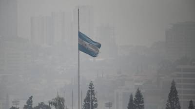 Una bandera nacional hondureña ondea en medio de una densa capa de humo que cubre Tegucigalpa el 6 de mayo de 2024.