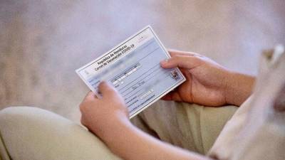 Un menor muestra su tarjeta de vacuna contra el coronaviurs.