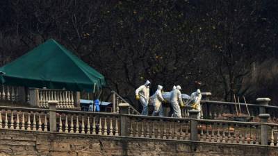 Un grupo de hombres usa trajes protectores mientras cargan el féretro de una persona fallecida por coronavirus en Tegucigalpa.