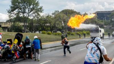 TOPSHOT - A Venezuelan opposition activist throws a molotov cocktail to a police water cannon truck during clashes within a march against President Nicolas Maduro, in Caracas on May 1, 2017.Security forces in riot vans blocked off central Caracas Monday as Venezuela braced for pro- and anti-government May Day protests one month after a wave of deadly political unrest erupted. / AFP PHOTO / FEDERICO PARRA