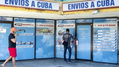 Dos personas frente a una agencia de viajes y servicios de carga a Cuba, en Hialeah, Florida.