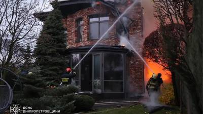 Equipos de emergencia apagan un incendio en el lugar del ataque con cohetes en Dnipro, Ucrania.