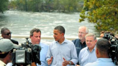 President Barack Obama, center, talks to reporters on the Temple Street Bridge over the Passaic River as he visits areas damaged by Hurricane Irene, Sunday, Sept. 4, 2011, in Paterson, N.J. Gov. Chris Christie stands left of Obama. (AP Photo/John O'Boyle, Pool)