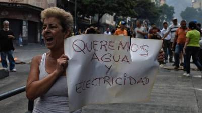 Una mujer sostiene un cartel mientras grita consignas durante una protesta en Venezuela. AFP