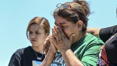 María López llora mientras visita un monumento improvisado en el lugar donde se descubrió el tráiler con migrantes adentro, en las afueras de San Antonio, Texas