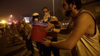 Ciudadanos forman una cadena humana para pasar baldes con agua y tratar de combatir el fuego, cerca de Vigo, Galicia.