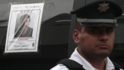 Un policía ante uno de los 100,000 carteles con la cara del 'Chapo' repartidos por todo México
