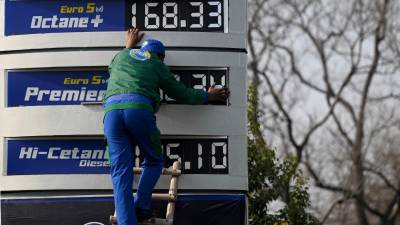 Un empleado de una gasolinera actualiza la última lista de precios de combustible después de un aumento en los precios de los productos derivados del petróleo.