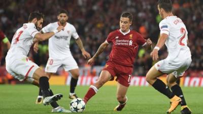 Liverpool's Brazilian midfielder Philippe Coutinho (C) vies with Sevilla's Argentinian defender Nicolas Pareja (R) during the UEFA Champions League Group E football match between Liverpool and Sevilla at Anfield in Liverpool, north-west England on September 13, 2017. / AFP PHOTO / PAUL ELLIS