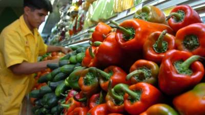 Un dependiente agrupa las verduras y frutas de un supermercado.