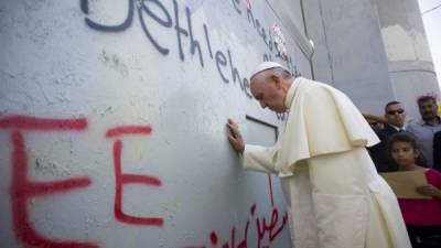 Francisco toca el muro que separa Cisjordania de Israel durante su visita a Belén.