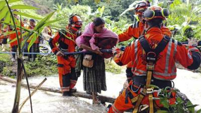Un grupo de bomberos ayuda a evacuar a las personas después de quedar atrapadas en un deslizamiento de tierra, luego del paso de la tormenta tropical Julia, en el pueblo de Queja, en San Cristóbal Verapaz, Guatemala.