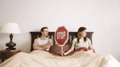Couple holding stop sign in bed
