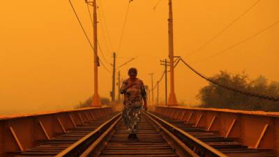 A woman walks on a bridge during the fires in Renaico, Araucania region, Chile on February 4, 2023. - Chile has declared a state of disaster in several central-southern regions after a devastating heat wave provoked forest fires that left four people dead, authorities said on Friday. (Photo by JAVIER TORRES / AFP)