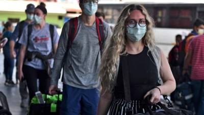 Passengers wear protective face masks to prevent the spread of the new Coronavirus, COVID-19, outside the Toncontin International Airport, in Tegucigalpa, on March 14, 2020. - Honduran government has prohibited citizens from Europe, China, Iran, and South Korea the entrance to the country. (Photo by ORLANDO SIERRA / AFP)