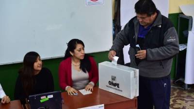 Un peruano deposita su voto en una urna con el logo del Onpe, el organismo electoral de Perú.