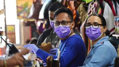 Prevención. Los trabajadores de una tienda usan mascarillas protectoras como precaución en el aeropuerto internacional Toncontín.(Photo by ORLANDO SIERRA / AFP)