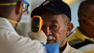 A doctor checks the temperature to a man at the Honduran Institute of Social Security (IHSS) to discard symptoms of the new Coronavirus, COVID-19, in Tegucigalpa, on March 13, 2020. - The Honduran government has suspended classes at schools and universities. (Photo by ORLANDO SIERRA / AFP)