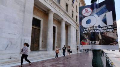 Transeúntes caminan frente a la sede del Banco de Grecia en Atenas. Foto: AFP