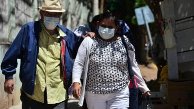 A couple wear protective face masks to prevent the spread of the new Coronavirus, COVID-19, as they head to the National Cardiopulmonary Hospital, in Tegucigalpa, on March 11, 2020. - Honduran Government announced the first two cases of the COVID-19 virus in the country. (Photo by ORLANDO SIERRA / AFP)
